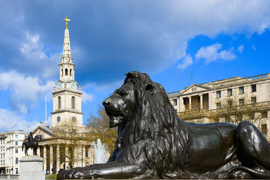 Bronze lion by Sir Edwin Landseer in Trafalgar Square with church spire of St Martin in the Fields in background