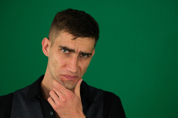 emotions of a handsome man guy on a green background chromakey close-up dark hair young man....