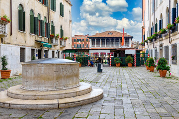 Old street with ancient water well on GrandÂ Canal in Venice, Italy. Architecture and landmark of Venice. Cozy cityscape of Venice. - 790256816