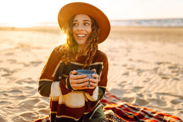 Young woman drinking morning coffee at picnic on the beach. Rest, relaxation, travel, lifestyle...