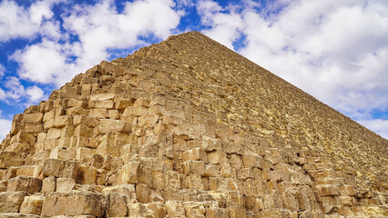 A upward view from the base of the Great Pyramid of Khufu with its huge tura limestone blocks against a brilliant blue sky on the Giza plateau 