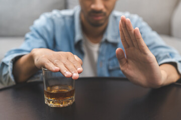 Alcoholism, depressed asian young man refuse, push out alcoholic beverage glass, drink whiskey, sitting alone at night. Treatment of alcohol addiction, having suffer abuse problem alcoholism concept.