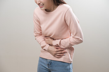 Flatulence asian young woman intolerance hand in stomach ache, suffer from food poisoning, abdominal pain and colon problem, gastritis or diarrhoea when at home. Patient belly, abdomen or inflammation - obrazy, fototapety, plakaty