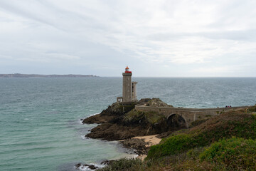 ue depuis le sentier côtier, le phare du Petit Minou se découvre au loin, surplombant l'horizon rocheux de la Mer d'Iroise, offrant une image emblématique de la côte bretonne, dans le Finistère.