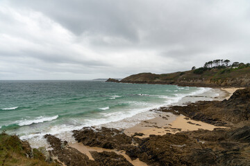 La plage du Petit Minou, entre sable et rochers, enchâssée entre les falaises de la Mer d'Iroise, incarne la beauté naturelle préservée du littoral breton. - obrazy, fototapety, plakaty