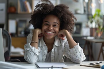 An engaging young woman with curly hair sitting at a desk with a white blouse, smiling at the camera