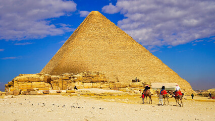 Tourists take a camel in the desert near the Great Pyramid of Khufu at Giza on bright day with...