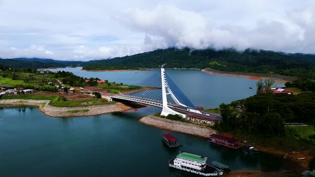 Drone of Jambatan Pulau Poh Bridge on Kenyir Lake surrounded by nature on a cloudy day in Malaysia