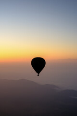 Sunrise in Morocco: A hot air balloon rises over desert dunes, illuminated by the dawn light.