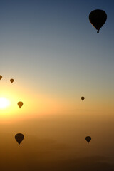 Sunrise in Morocco: A hot air balloon rises over desert dunes, illuminated by the dawn light.