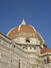 View of the domed roof of the Santa Maria del Fiore duomo in Florence, Italy set against a deep blue sky.