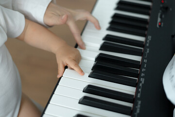 child's and adult's hands on piano keys, close-up