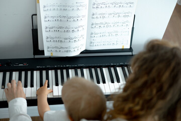 child's and adult's hands on piano keys, close-up