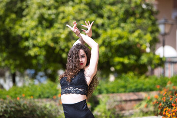 Beautiful woman with long curly hair, dancing flamenco artfully in a park in Seville, Spain....