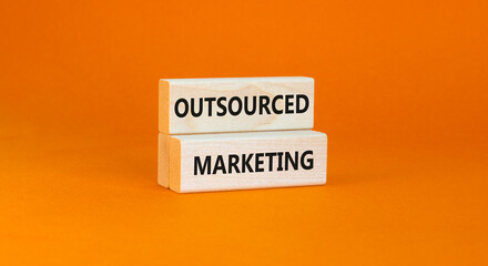 Outsourced marketing symbol. Concept words Outsourced marketing on beautiful wooden blocks. Beautiful orange table orange background. Business Outsourced marketing concept. Copy space.