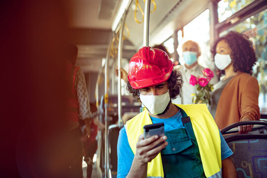 Construction worker in hard hat using smartphone on public bus