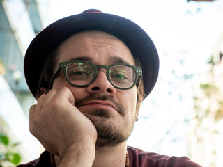Portrait of Thoughtful Man with Hat and Glasses looking at camera. 