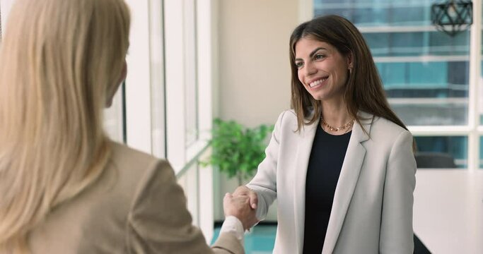Latina bank analyst or advisor shaking hands company client, start formal meeting in office. Parties establish partnership, buy or sell services, express regard and recognition, get professional help