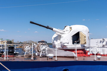 The artillery gun on the deck of the warship.