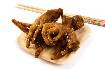 A bamboo plate of soy sauce cooked Asian boneless chicken feet with chopsticks isolated on white