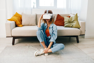 Smiling Woman with Virtual Reality Glasses enjoying a Futuristic VR Game on a Sofa in the Comfort...