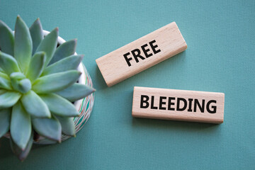 Free bleeding symbol. Concept words Free bleeding on wooden blocks. Beautiful grey green background...
