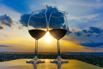 Wine Glasses in Sunset Rays with Cityscape Background