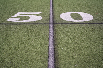 fifty yard line marker on a green turf outdoor football field