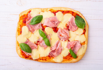 Traditional italian pizza with ham mozzarella and  basil