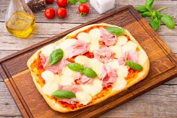 Traditional italian pizza with ham mozzarella and  basil