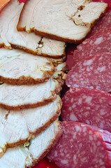Slices of delicious smoked sausage and meat with pepper and seasoning lie on a plate.