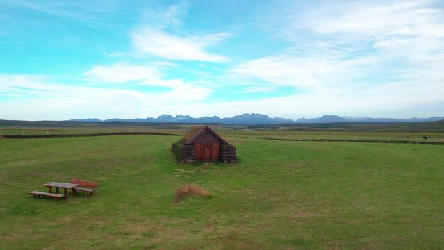 Traditional Viking Turf House Church in Iceland. Drone Circles Norwegian Grass Covered Roof Hut On A Sunny Day with Green Grass.