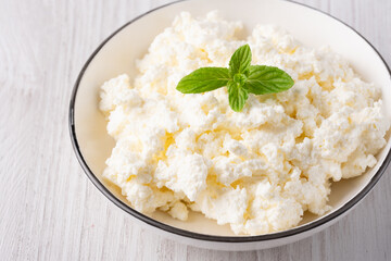 Cottage cheese in a plate on a white table, with copy space for text