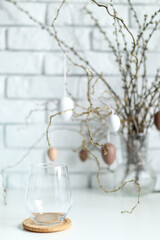 Easter decoration made of willow twigs and white-brown eggs and catkins, on a background of white bricks
