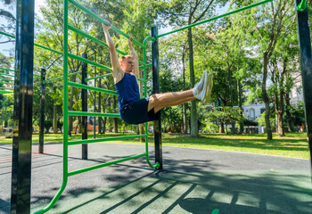 Young guy athlete exercising on sports equipment in the park