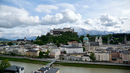 Blick auf die Festung Salzburg vom Kapuzinerberg mit der Altstadt und lockerem wolkigem Himmel bei Sonnenschein