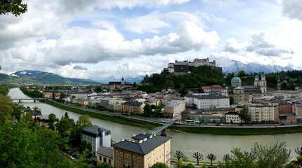 Blick auf die Festung Hohensalzburg in Salzburg vom Kapuzinerberg mit der Altstadt und lockerem wolkigem Himmel bei Sonnenschein