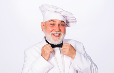 Smiling chef, cook or baker in uniform and chef hat in kitchen restaurant and hotel. Male chef in white hat adjust bow tie. Restaurant advertising. Cooking, food preparation and professional culinary.