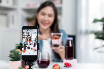 Selective focus smartphone with smiling young beautiful Asian reviewing mixed strawberry and cherry...