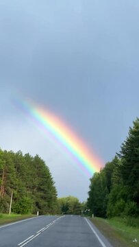 A double rainbow on a rainy spring day. A multicolored rainbow over a floral green field in the Perm Region. A rainbow against a cloudy sky.