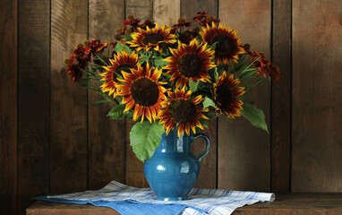a bouquet of sunflowers in a jug on the table on a dark wooden background.