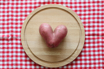 heart-shaped potatoes on a red checkered tablecloth, top view. flat lay.