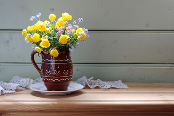 forget-me-nots and globe flowers in a jug on the table, a rural still life.