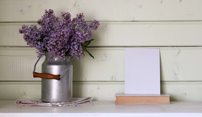 bouquet of lilacs in a can and an empty postcard on the table. mockup, creator of scene. empty space for your text.