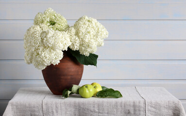 bouquet of hydrangeas and green apples on the table in the cottage, a summer still life with garden flowers.
