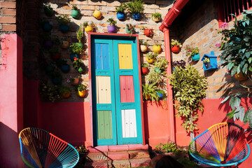 Backyard wall decorated with a colorful wooden door, easy chairs and a vertical garden. False...