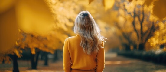 A woman in a yellow sweater and jeans walking on a path