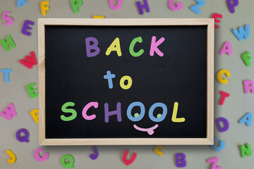 Back to School. Chalk inscription on blackboard on background of multi-colored letters. Concept of beginning of school year. First day of preschool. Welcome text.