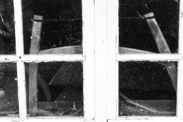 Old wooden tools behind the window. A soft handle is visible through the dusty window horizontal.
