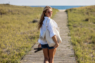 Beautiful young woman walking to the beach while looking at camera